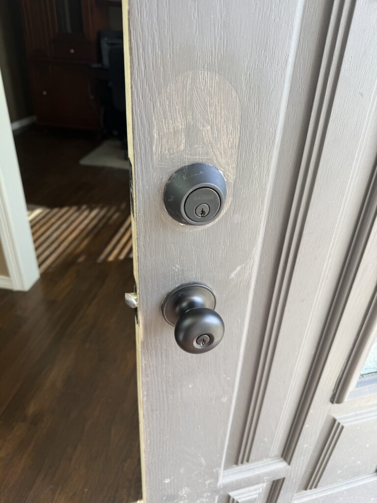 Deadbolt and doorknob on a white residential entry door