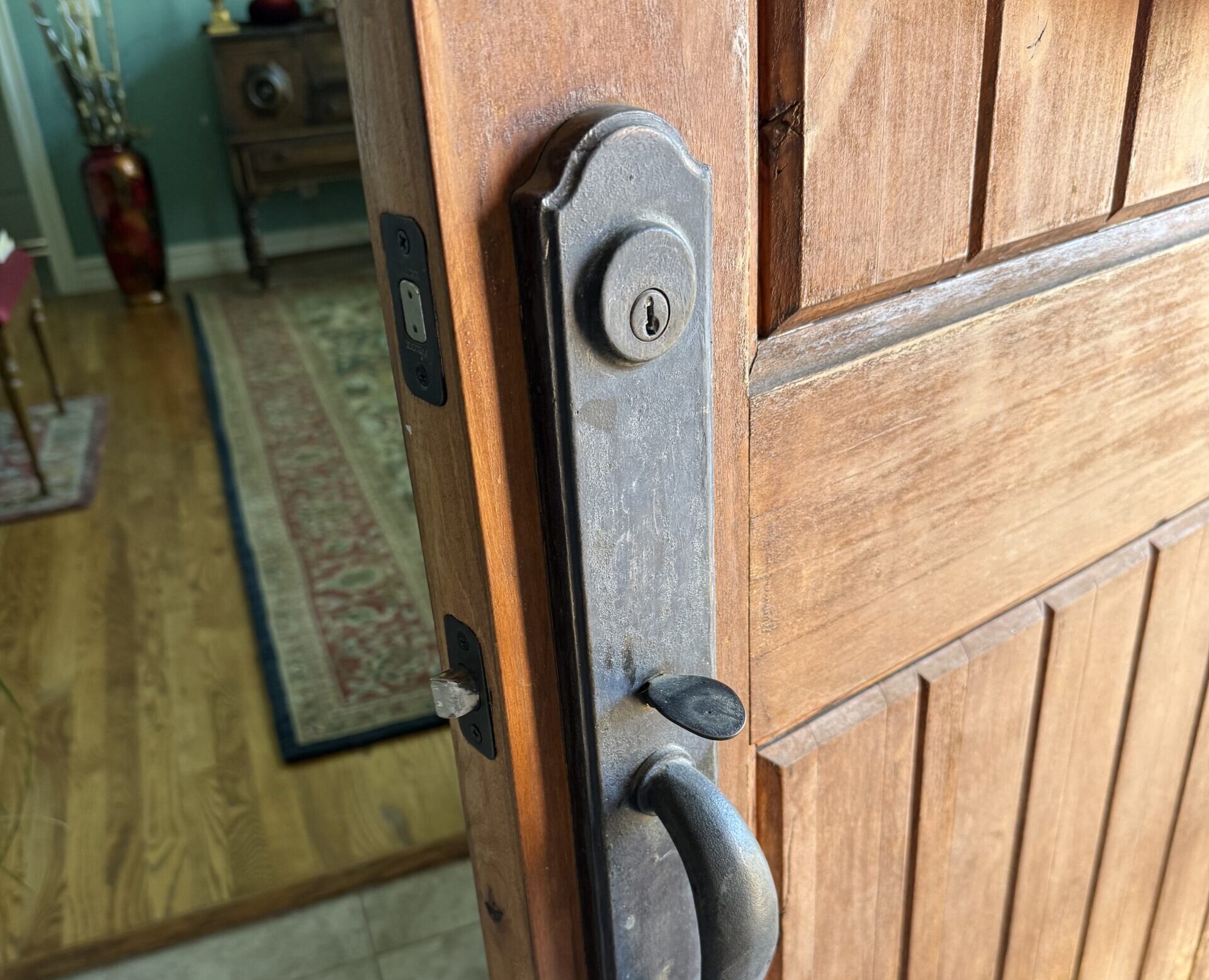 Deadbolt and handle set on a wooden front door during lock repair in Broken Arrow