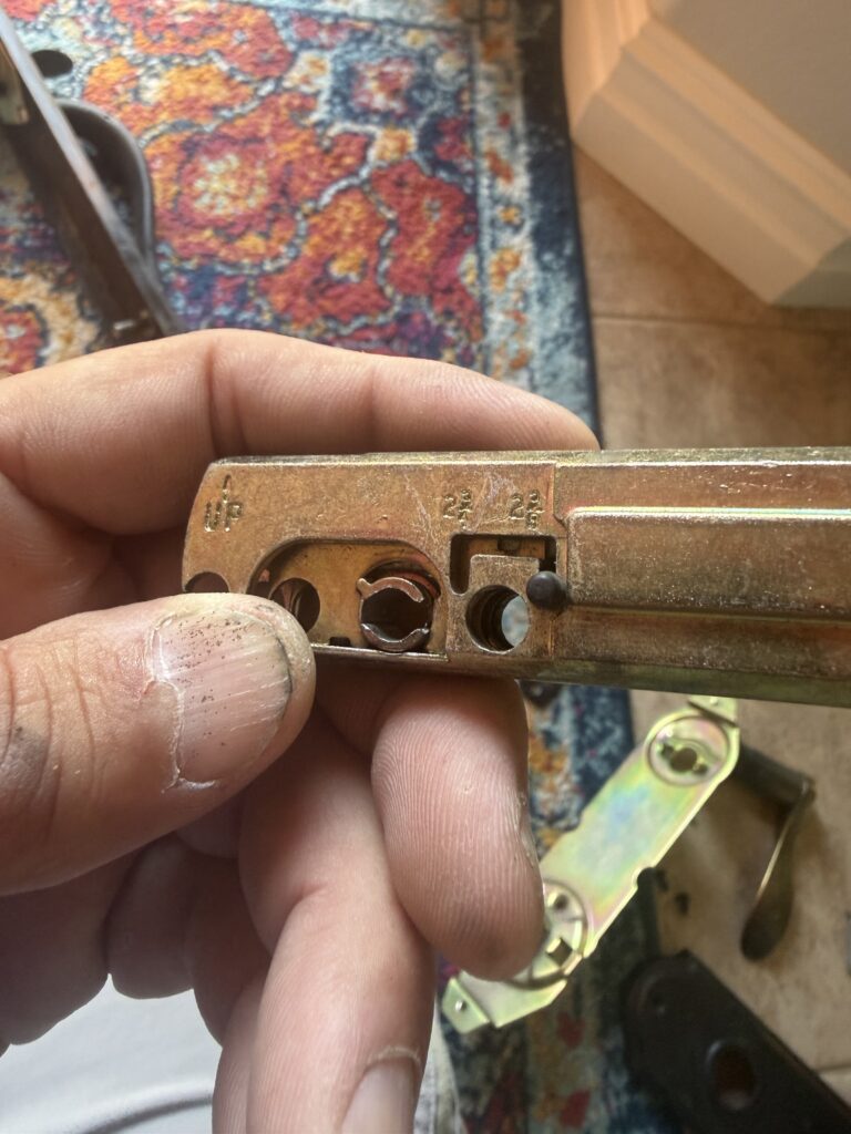 Removed front-door deadbolt latch showing its internal mechanism during repair in Broken Arrow