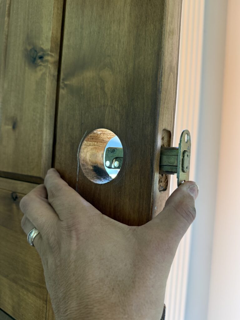 Deadbolt latch being fitted into a wooden front door during repair in Broken Arrow