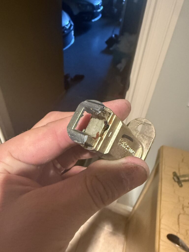 Broken spring latch removed from the door to the garage during lock repair in Broken Arrow