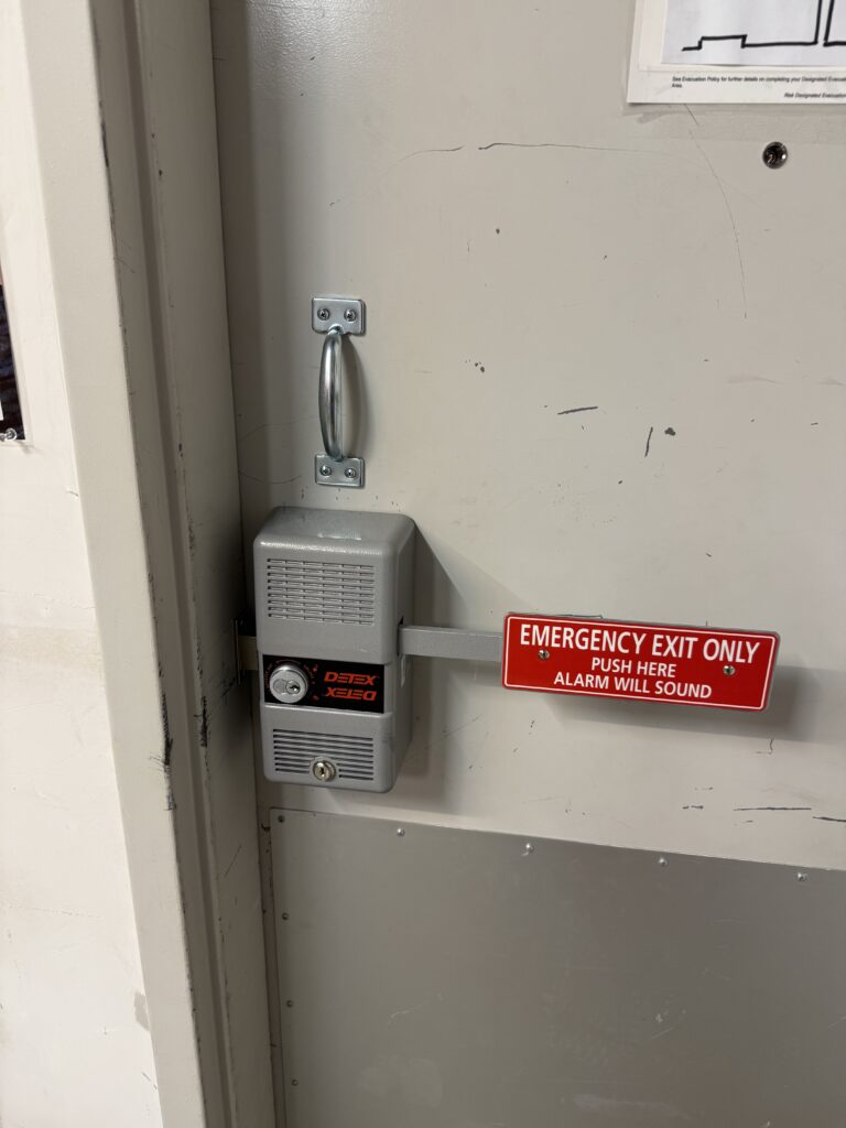 Repaired Detex exit alarm with a separate pull handle installed on a commercial door in Jenks