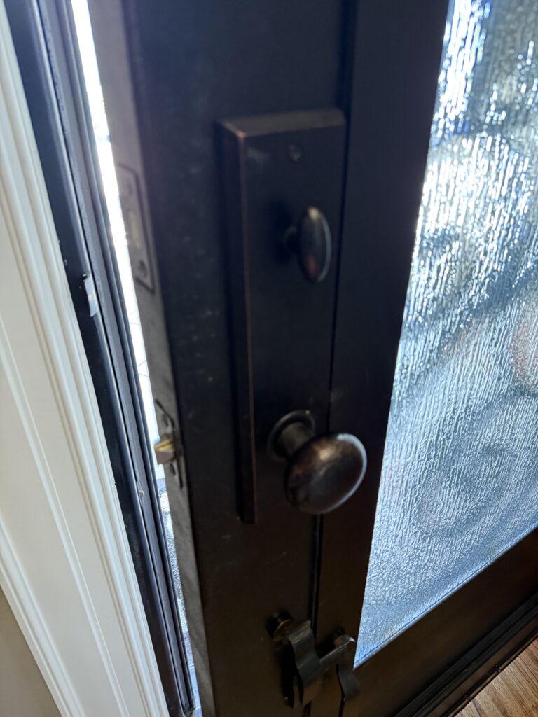 Interior lock trim on a metal front door after spring latch replacement in Broken Arrow