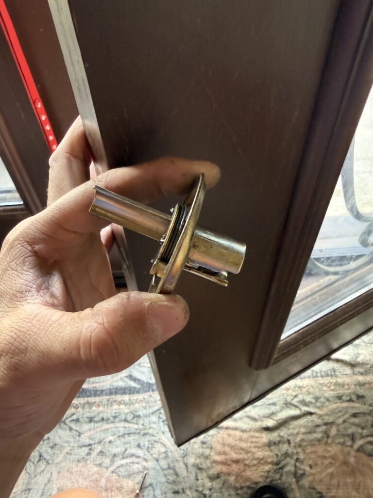 Removed front door lever assembly held during lock spring repair in Broken Arrow
