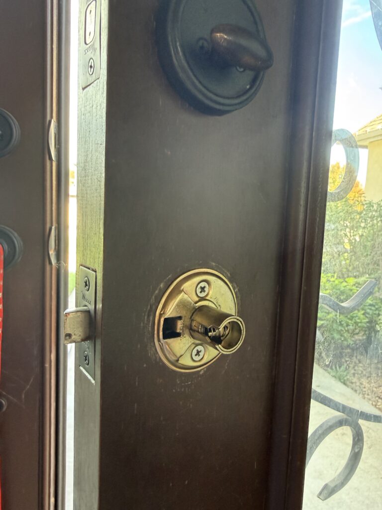 Front door lock with the return spring assembly exposed during repair in Broken Arrow
